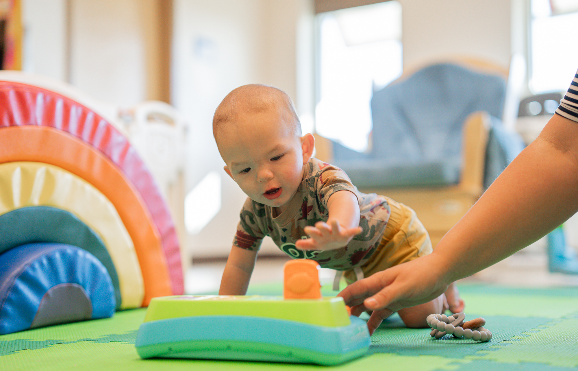 A young baby crawls and plays with toys during class