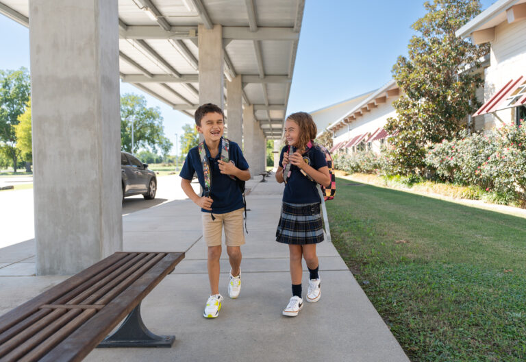 Two students laugh as they walk outside to the car line to get picked up from school