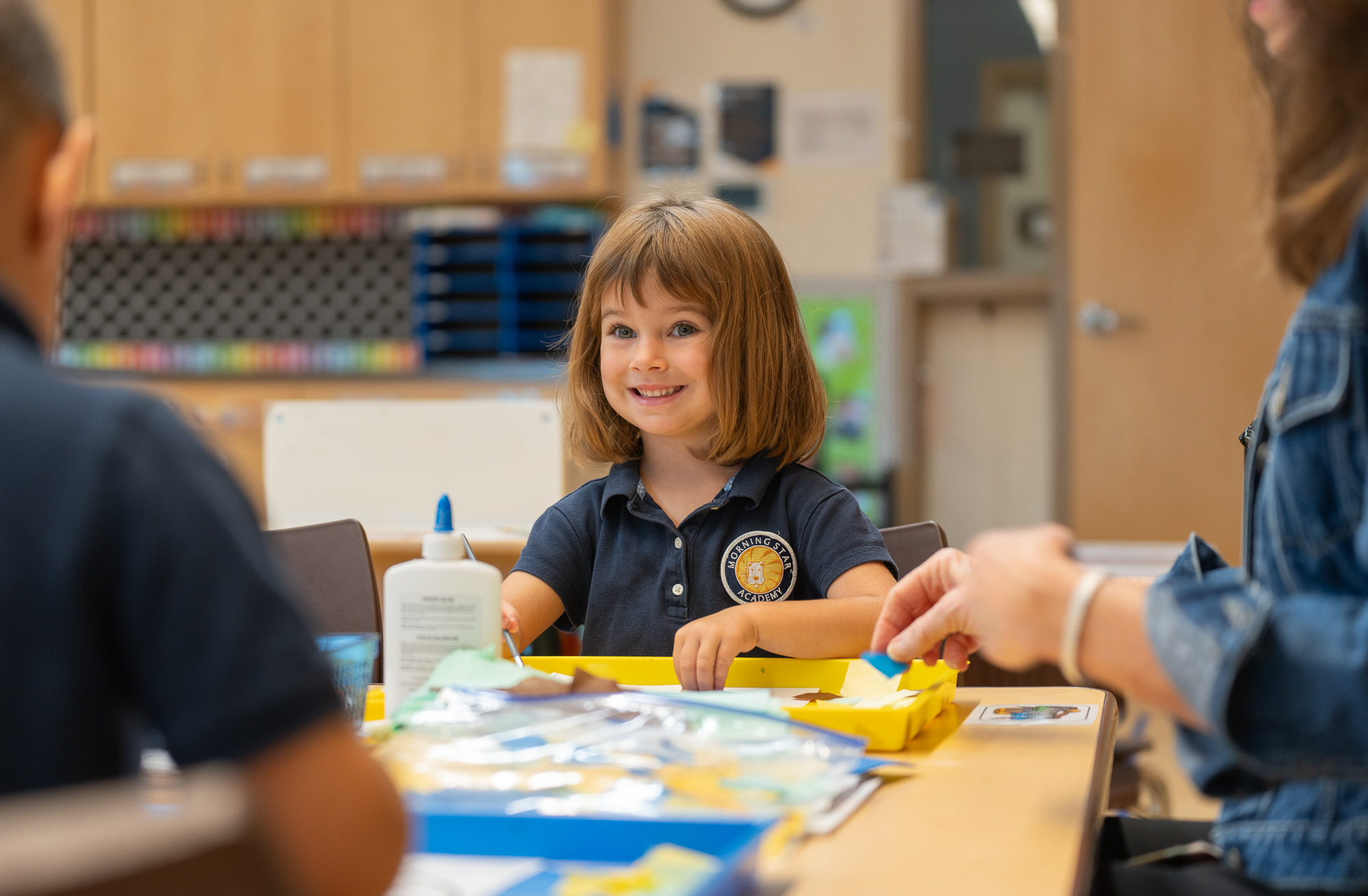 A young student smiles as she works on arts and crafts during school