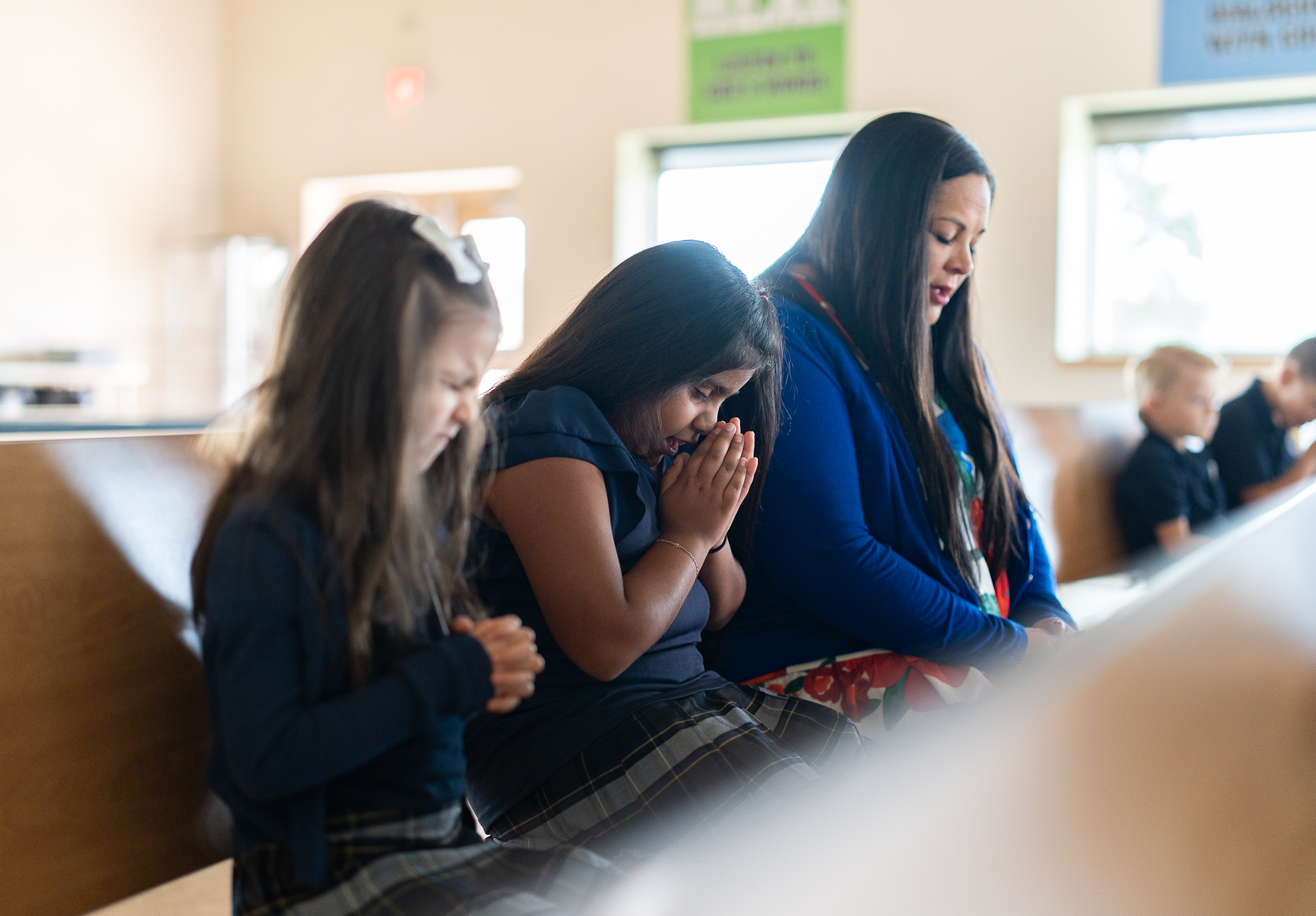 Students sit together with their teacher while they pray together during school